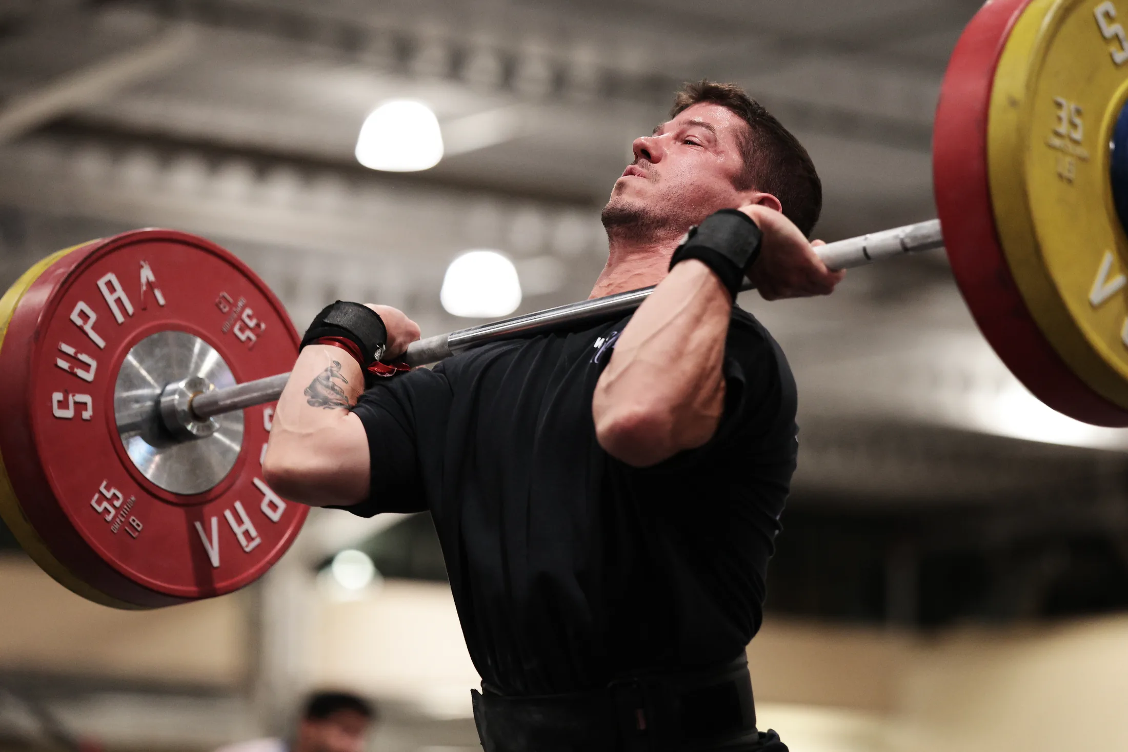 An athlete mid-lift under a loaded barbell on the floor